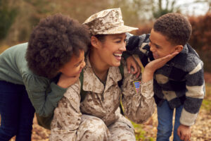 American Female Soldier In Uniform Returning Home On Leave To Family Greeted By Two Children