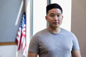 A serious mid adult male veteran poses for a portrait with the American flag in the background.